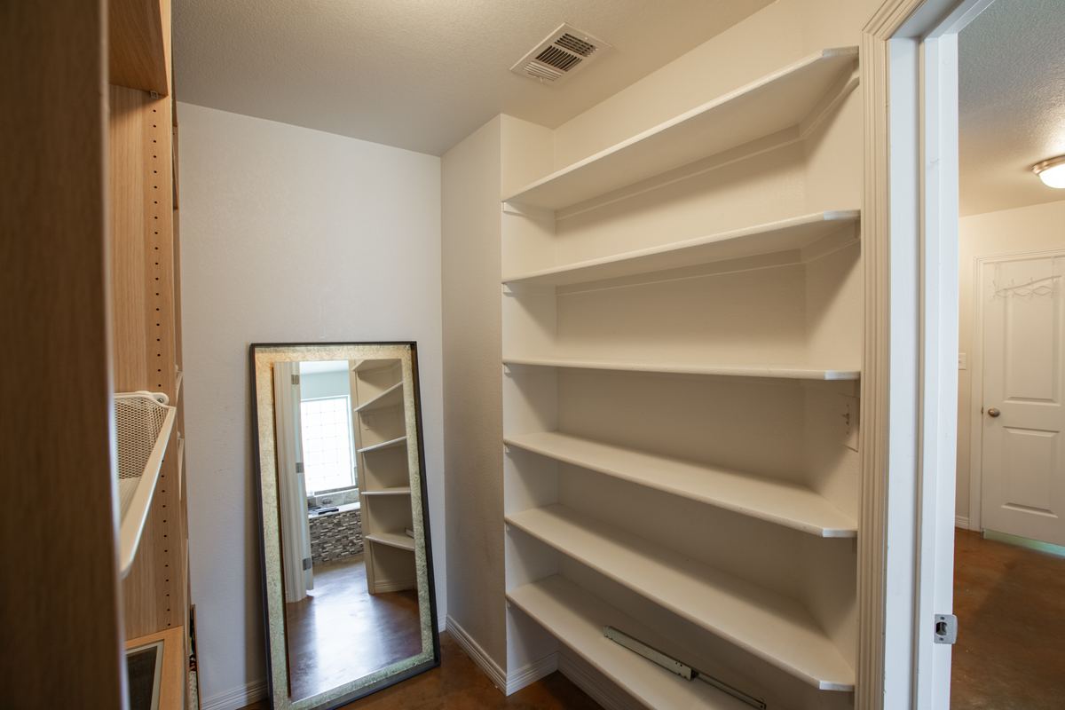 Walk-in closet with built-in shelving and a full-length mirror