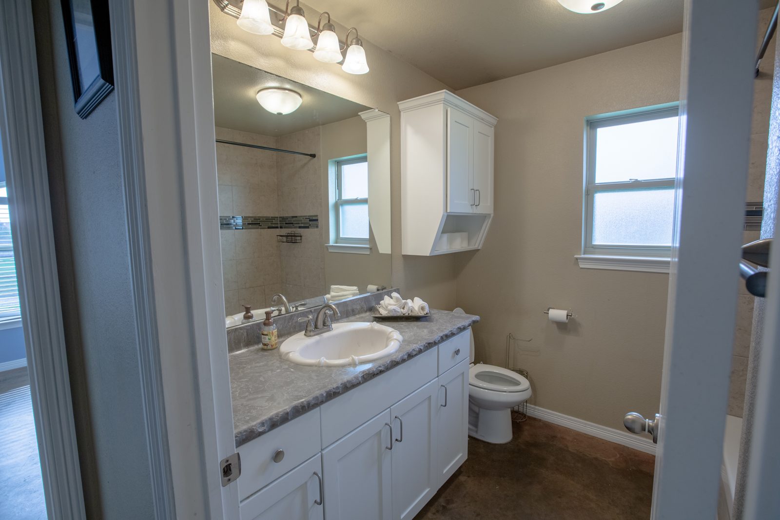 Guest bathroom with white vanity, large mirror and tub-shower combo