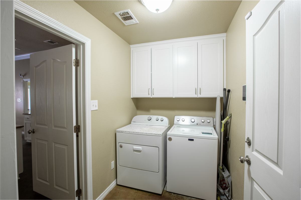 Laundry room with full-size washer and dryer and white cabinets