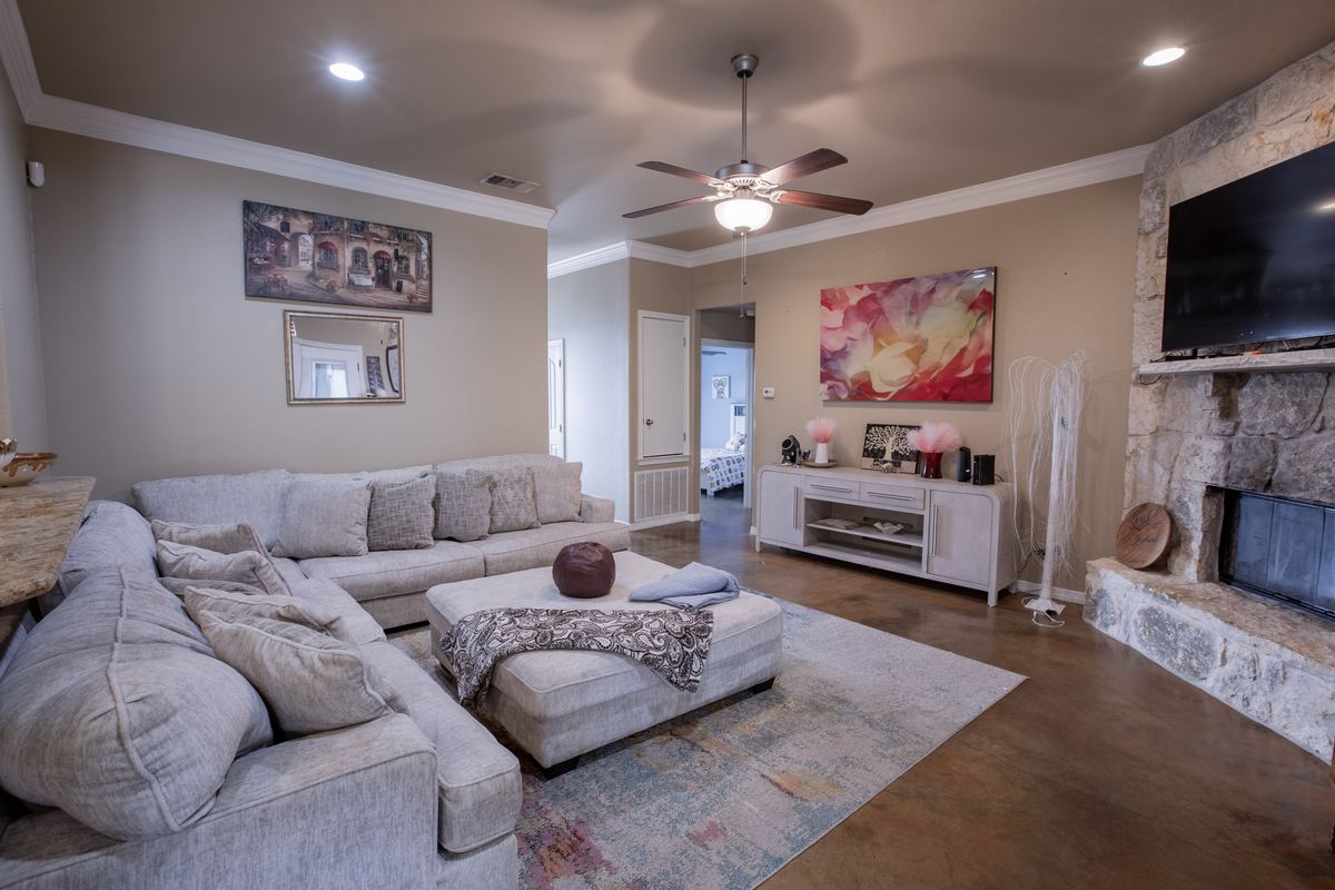 Living room with sectional sofa, stone fireplace and wall-mounted TV
