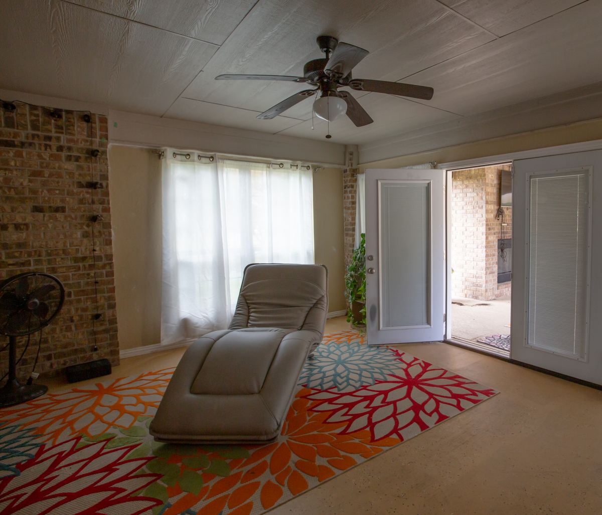 Sitting room with a lounge chair, bright rug and French doors opening to the covered patio